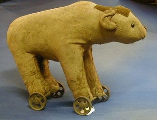 A 19th Century "Steiff" type bear raised on 4 iron wheels 11"