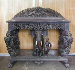 An Indian carved and pierced "rosewood" and ebony hall table, with raised pierced back, the base carved a figure of an elephant with attendant raised on 4 carved supports in the form of mythical figures 42" 