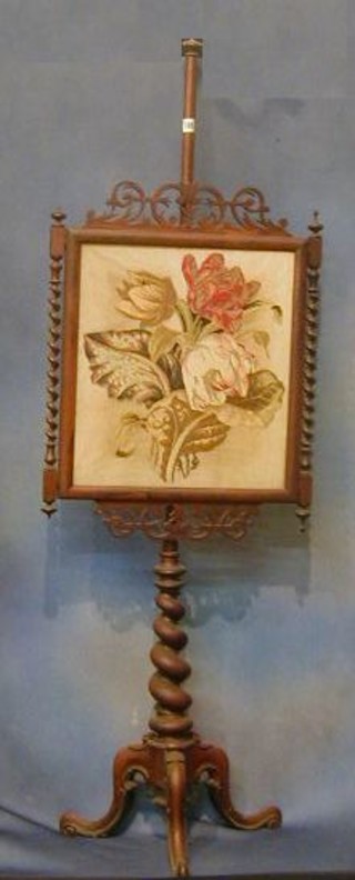 A Victorian pole screen with Berlin wool work panel contained in a rosewood frame with spiral turned decoration, raised on a spiral turned column with tripod supports