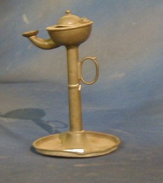 A pewter oil lamp raised on a circular base 7"