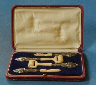 A cased set of 4 Edwardian ivory and silver mounted massage implements including rollers and probes