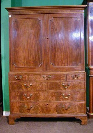 A George III mahogany linen press with moulded cornice, the interior fitted 2 shelves above 5 short and 2 long drawers enclosed by panelled doors, raised on bracket feet 60"