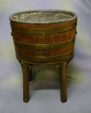 An 18th/19th Century oak oval coopered wine cooler with zinc lining and brass banding, raised on a later mahogany stand 20"