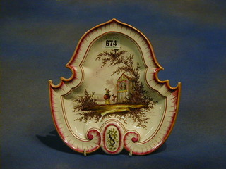 A 19th Century shaped faience plate decorated a Punch and Judy theatre, the reverse marked VP, 9"