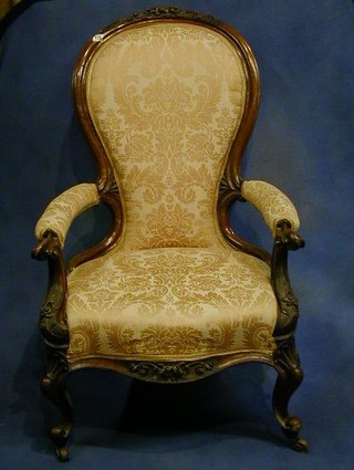 A Victorian carved walnutwood show frame open arm chair upholstered in pink material on cabriole supports