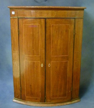 A Georgian inlaid mahogany bow front hanging cabinet, the interior fitted shelves enclosed by a panelled door 31"