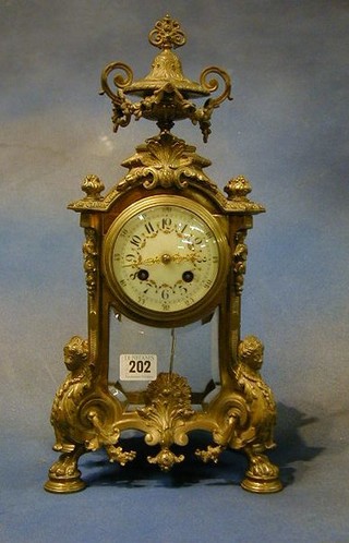 A 19th Century French 8 day striking 4 glass clock, the enamelled dial with Arabic numerals and floral garland decoration contained in a gilt Ormolu case surmounted by a lidded urn