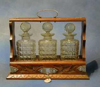 A Victorian carved oak tantalus with silver plated mounts complete with 3 decanters