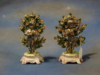 A pair of 19th Century Continental silvered porcelain figures of standing cherubs with baskets beneath an arbour 8"   