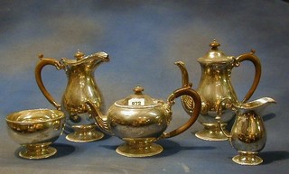 A silver 5 piece tea service of circular form comprising teapot, coffee pot, cream jug, sugar bowl, hotwater jug with bead work borders and beech wood handle, London 1925 and 1926 by Garrard Co monogrammed K, 82ozs