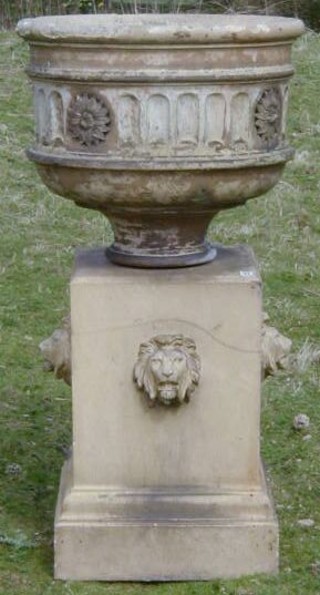 A 19th Century carved stone garden urn with niched and floral decoration, raised on a square base carved lions heads 39"
