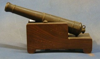 A 19th Century bronze model firing canon 12" raised on a wooden trunion