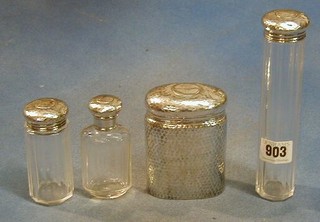A planished silver oval dressing table jar London 1912, a cut glass pin jar with silver top and 2 cut glass dressing table jars with silver tops (4)