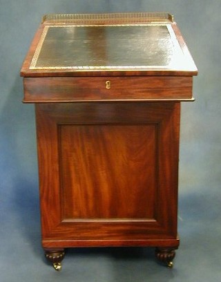 A Regency mahogany Davenport desk with brass three-quarter gallery and inset tooled leather writing surface, the sliding top with hinged lid revealing a well fitted interior having an ink well drawer, fitted 2 brushing slides and the pedestal fitted a cupboard with 3 long drawers, raised on bun supports 20"