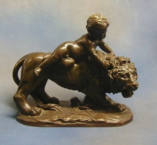 A bronze figure of a lion with a naked boy on its back, raised on an oval naturalistic base 11"