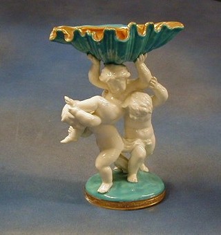 A 19th Century Mores porcelain table centre piece in the form of 3 cherubs supporting a scalloped shaped shell, the base impressed  Mores and marked Thomas Goode & Co. 10" (slight crack to base