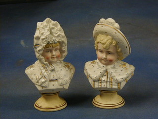 A pair of 19th Century biscuit porcelain head and shoulders portrait busts of bonnetted children 7" raised on circular socle bases (slight crack to 1)