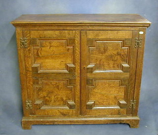 A 19th/20th Century oak Jacobean style cabinet, the shelved interior enclosed by panel doors, raised on bracket feet 36"