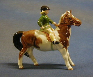A Beswick figure of a Piebald horse being ridden by a young girl