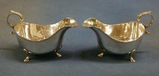 A pair of silver sauce boats with C scroll handles, raised on hoof feet by Walker & Hall, Sheffield 1960, 5 ozs