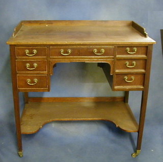 A 19th Century mahogany  kneehole desk/dressing table with three-quarter gallery above 1 long and 6 short drawers, raised on square tapering supports ending in brass caps and casters and with undertier 33"