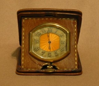 A 1920's enamelled travelling clock in a leather case