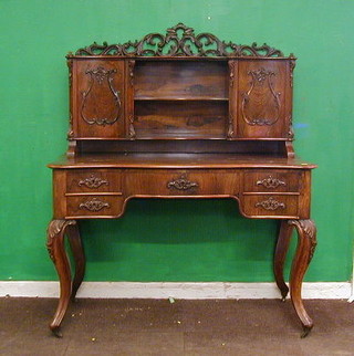 A Victorian French rosewood bonheur du jour, the raised back with pierced fret work decoration, fitted a niche, flanked by a pair of cupboards enclosed by panelled doors, the base of serpentine outline, fitted 1 long drawer flanked by 4 short drawers, raised on French cabriole supports 47"