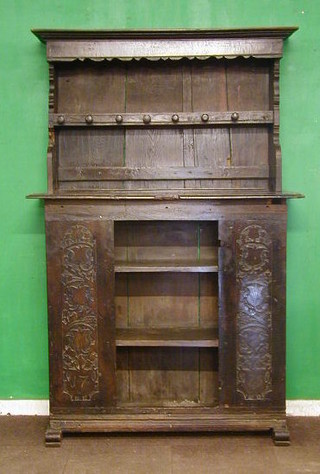 An 18th Century oak dresser, the later raised back with moulded cornice and 2 shelves, the base fitted a cupboard having carved decoration to the sides, the base dated 1775 54"
