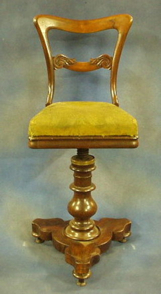 A childs Victorian rosewood spoon back revolving chair with carved mid rail and upholstered seat, on a triform base