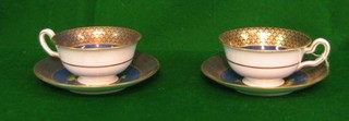 A pair of Copeland Spode blue ground cups and saucers with gilt banding and decorated birds amidst flowering branches