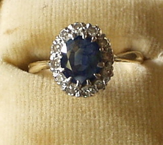 A lady's 18ct gold dress ring inset an oval cut sapphire surrounded by numerous diamonds