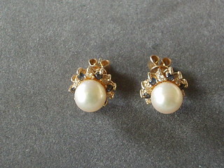 A pair of pearl earrings surrounded by sapphires and diamonds