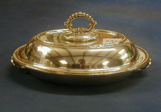 An oval silver plated entree dish and cover with bead work border