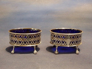 A  pair of Victorian pierced oval salts raised on ball and claw supports with cut blue glass liners, Sheffield 1888 4 ozs