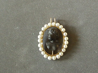 A  19th Century shell carved cameo bust of a child, contained in a gilt pendant supported by pearls