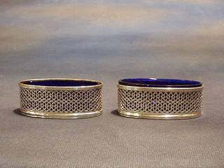 A pair of pierced oval silver plated salts with blue glass liners