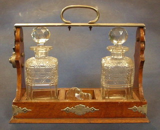 An Edwardian oak and silver plated cut glass 3 bottle tantalus (fitted 2 cut glass bottles)