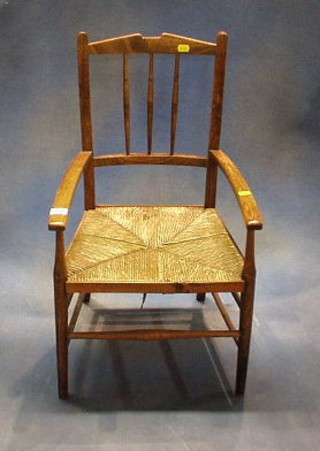 A childs elm stick and rail back carver chair with woven rush seat