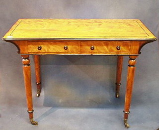 A Victorian satinwood writing table with ebonised stringing fitted 2 drawers on turned supports ending in brass caps and castors by Holland & Sons 42"