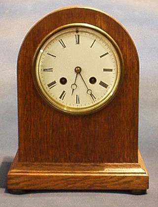 A Victorian 8 day striking mantel clock with enamelled dial and Roman numerals contained in an arched oak case