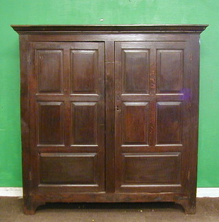 A 17th/18th Century oak cabinet of panelled construction with moulded cornice, enclosed by panelled doors, 59"