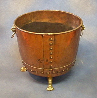 A circular copper log bin, raised on brass paw supports 19"