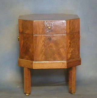 A Georgian mahogany octagonal wine cooler with brass drop handles, raised on a stand with square column supports ending in brass caps and castors 20"