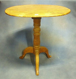 A Continental oval walnutwood wine table raised on a carved column and tripod supports 28"
