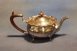 A circular silver plated teapot raised on trifid supports with beech handle