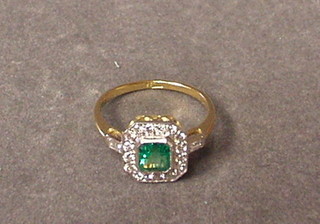 A lady's gold dress ring set a square cut emerald surrounded by numerous diamonds set baguette diamonds to the shoulders