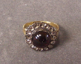 A lady's gold dress ring set a cabouchon cut garnet surrounded by 16 diamonds
