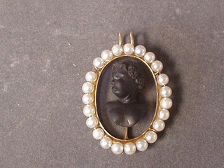 A  19th Century shell carved cameo bust of a child, contained in a gilt pendant supported by pearls