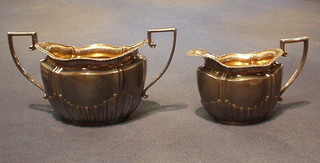 An Edwardian silver twin handled sugar bowl and matching cream jug with demi-reeded decoration Sheffield 1904, 10 ozs