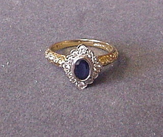 A lady's gold dress ring set an oval sapphire surrounded by diamonds